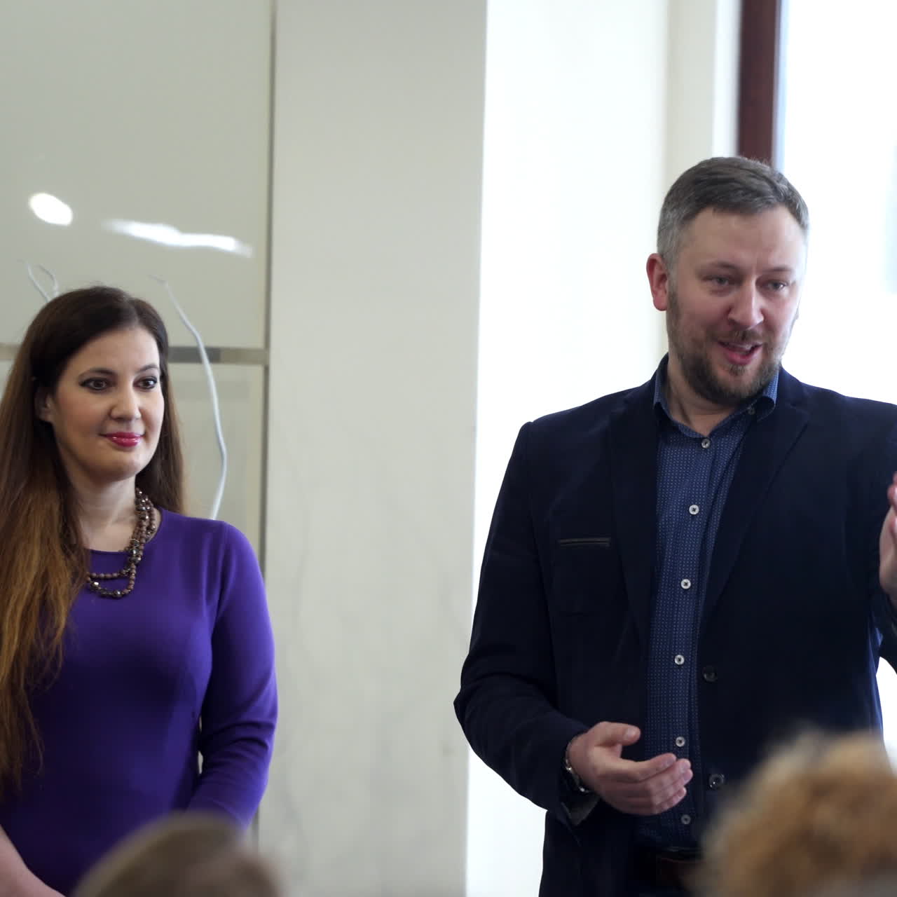Educators tell the speech at conference. Business people seminar. Public audience listening to successful leaders. Young woman coming into the stage in auditorium.