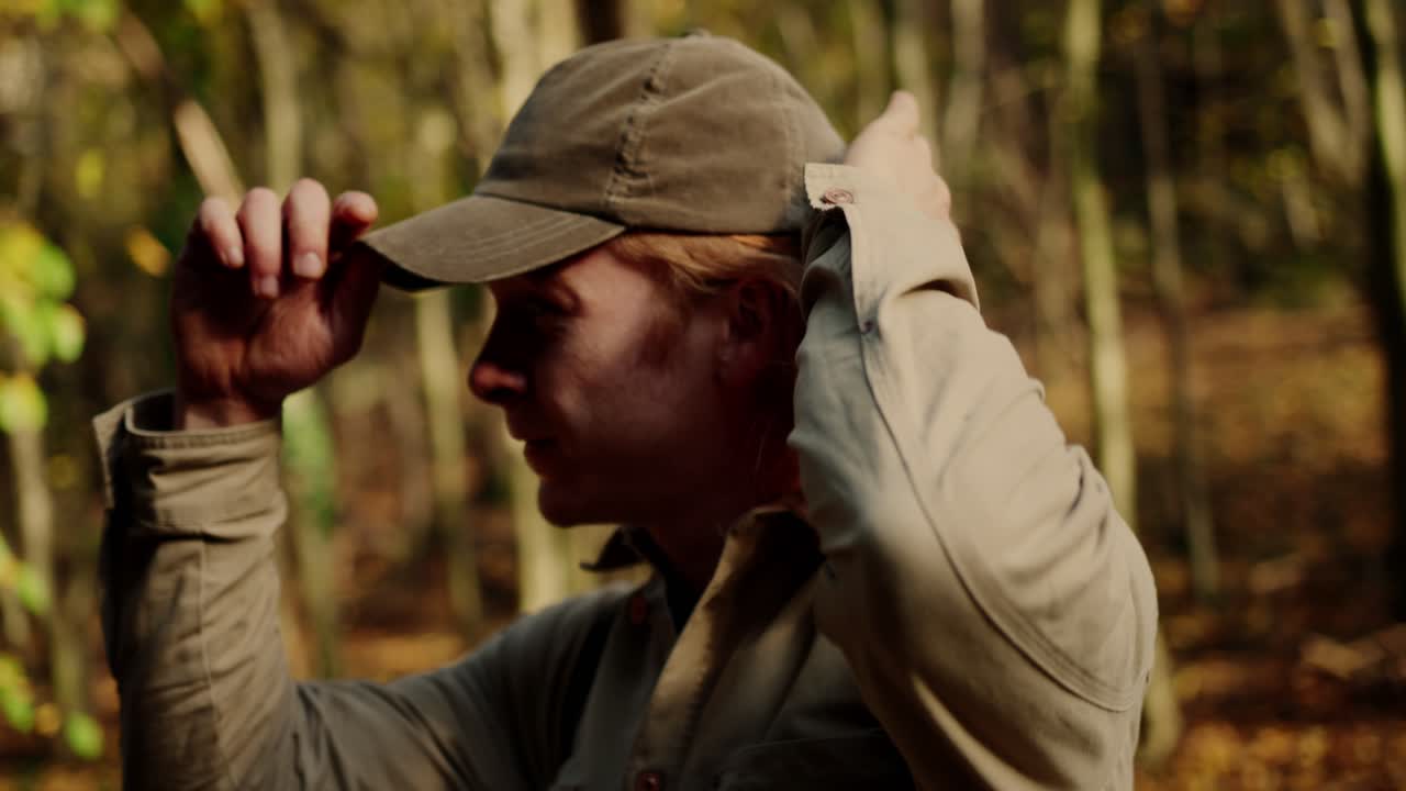 등산객의 중간 클로즈업 샷이 셔츠 단추를 풀고 금발 머리를 정리하는 dürnstein