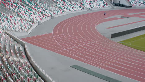 mujer caucásica practicando correr en una pista vacía del estadio temprano en la mañana. fotografiado con lente anamórfica