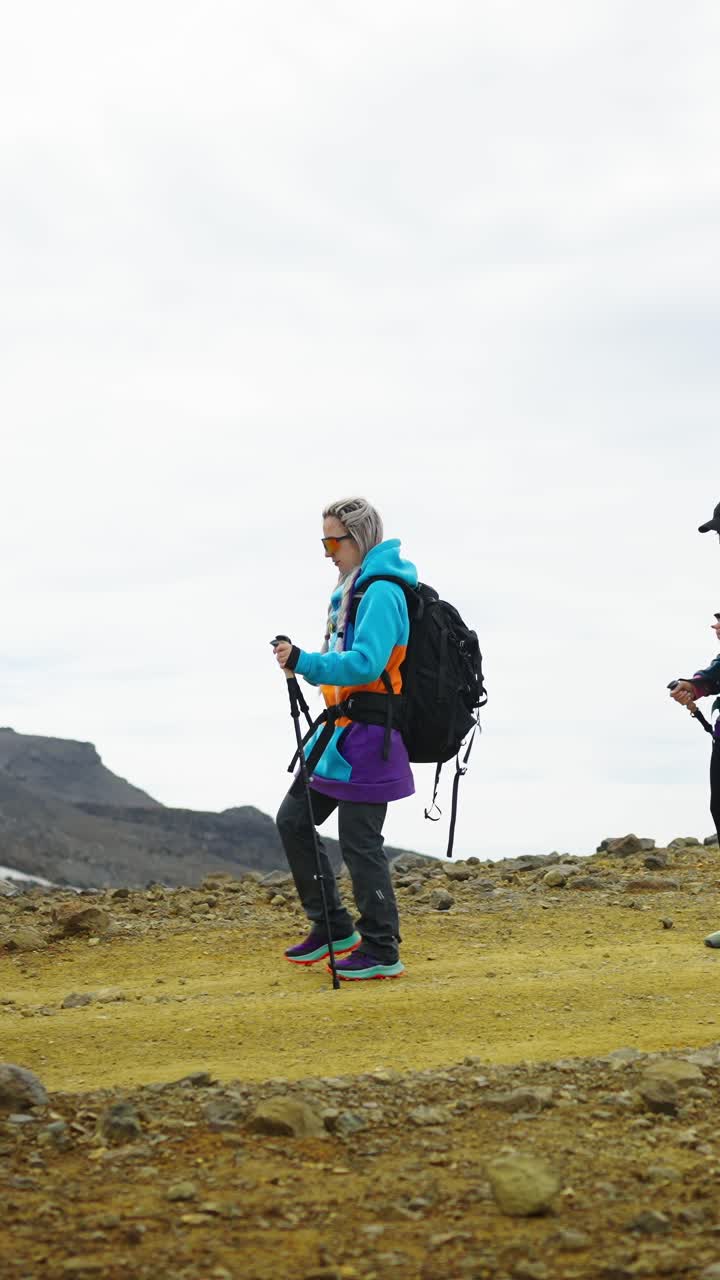 Due donne e un cane in escursione su un sentiero di montagna roccioso