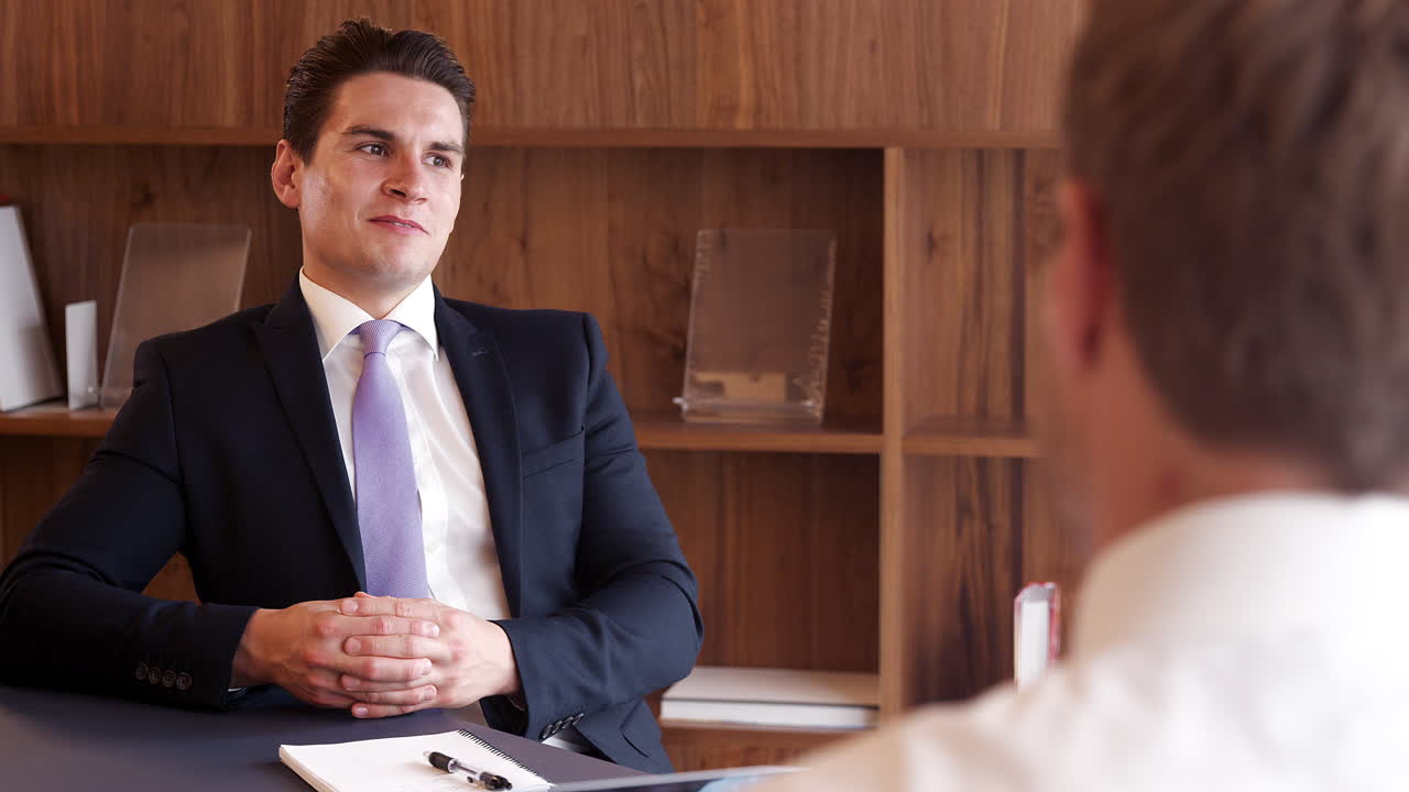사업가가 대학원 채용 평가 날 사무실에서 남성 후보자를 인터뷰하고 있습니다.