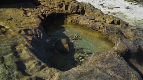 pequeña piscina de roca durante la hora dorada recortada por años de erosión, roca antigua
