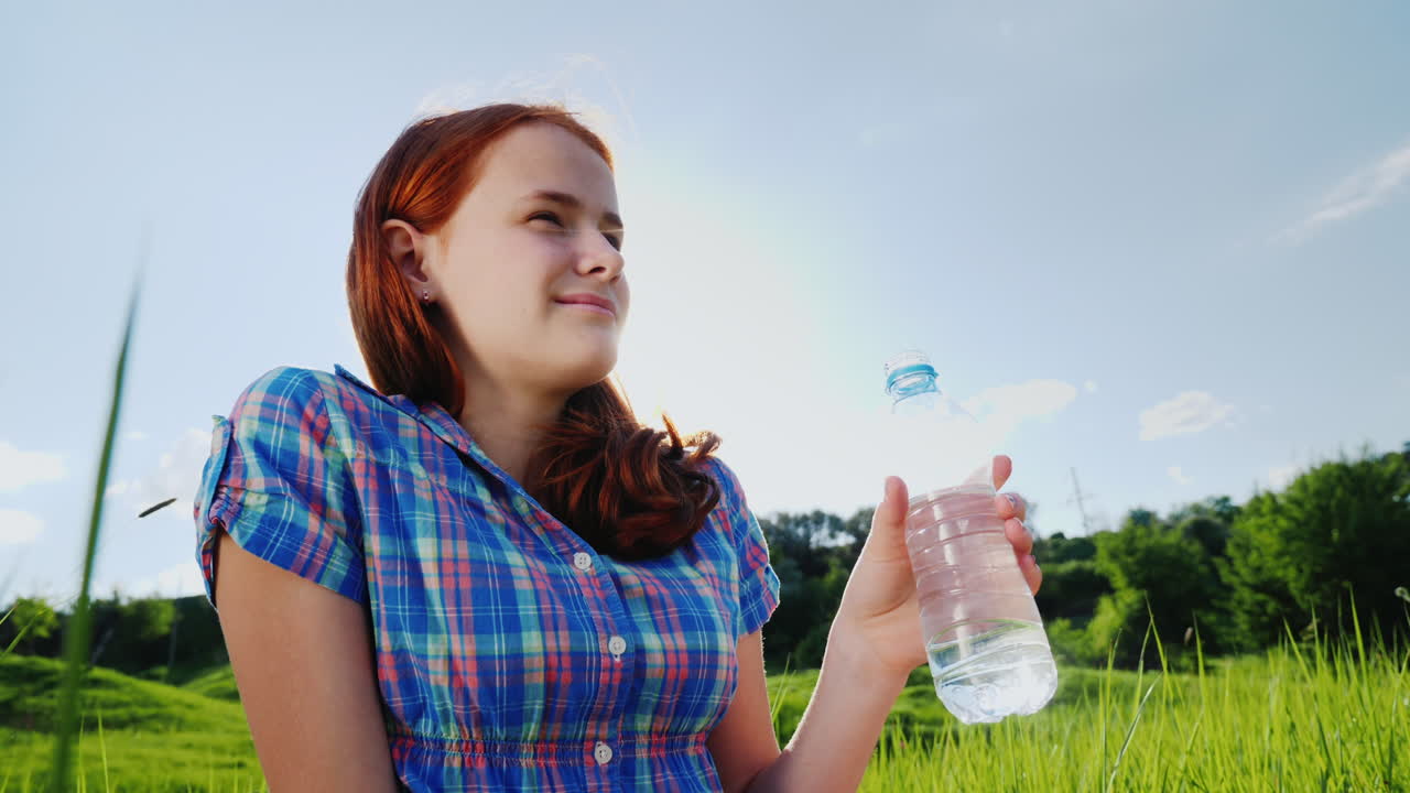 한 십대가 그림 같은 장소에서 소풍을 가면서 병에서 깨끗한 물을 마신다 2