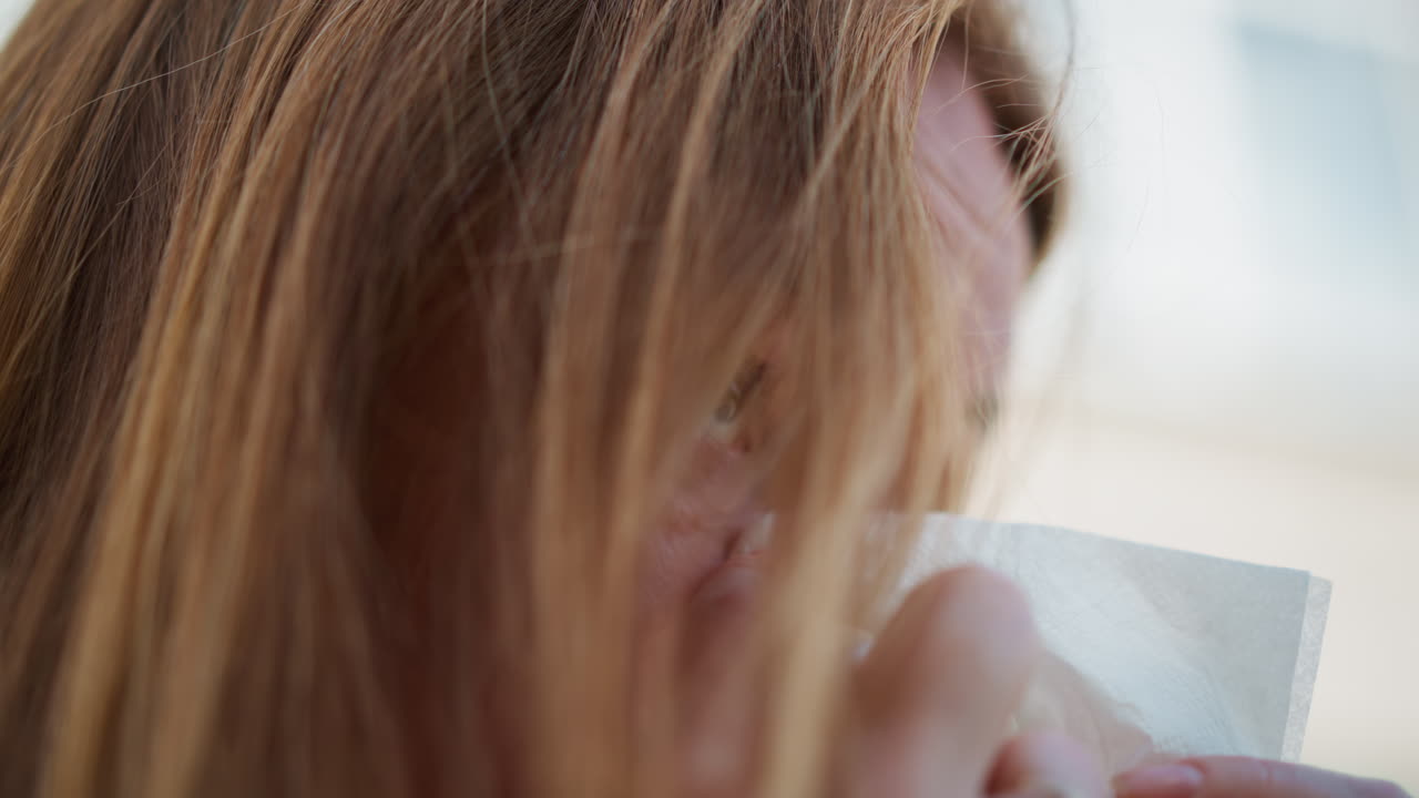 Extreme close up of crying student wiping tears with napkin, emotional young woman expressing deep sadness and vulnerability, tearful face partially hidden by hair