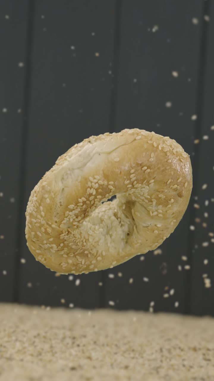 Sesame seeds sprinkling over a floating bagel in commercial