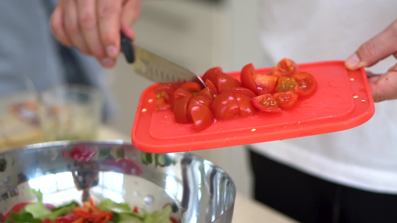Chef Putting The Fresh And Chopped Red Tomatoes Into A Stainless Bowl For Vegetable Salad. close up shot