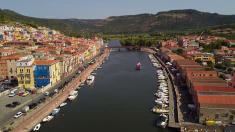 flyover aerial drone flying above river temo in touristic town of bosa, sardinia