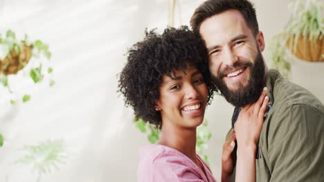 video portrait of happy diverse couple in living room embracing and smiling, with copy space