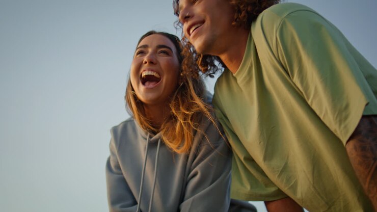 glückliche jugendliche küssen den blauen himmel im hintergrund. junge frau wirft einen stein