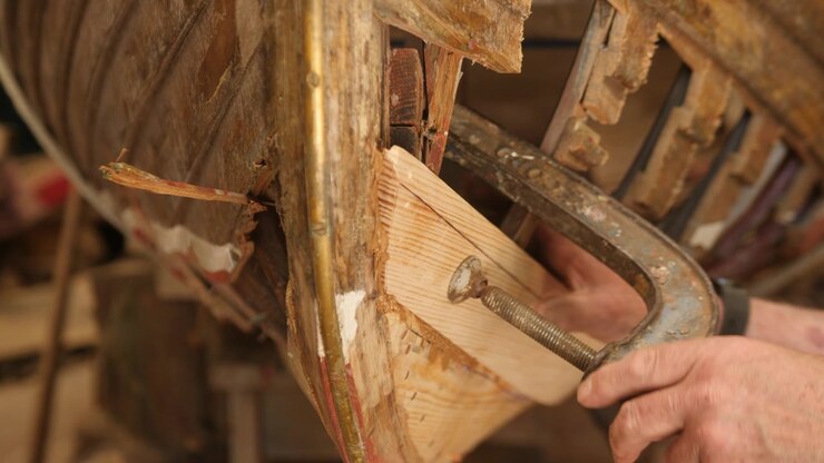 Securing pine plank to wood boat hull using clamp