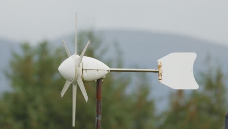 a compact wind turbine spins steadily in a rural landscape, with overcast daylight and gentle camera stability highlighting renewable energy in action