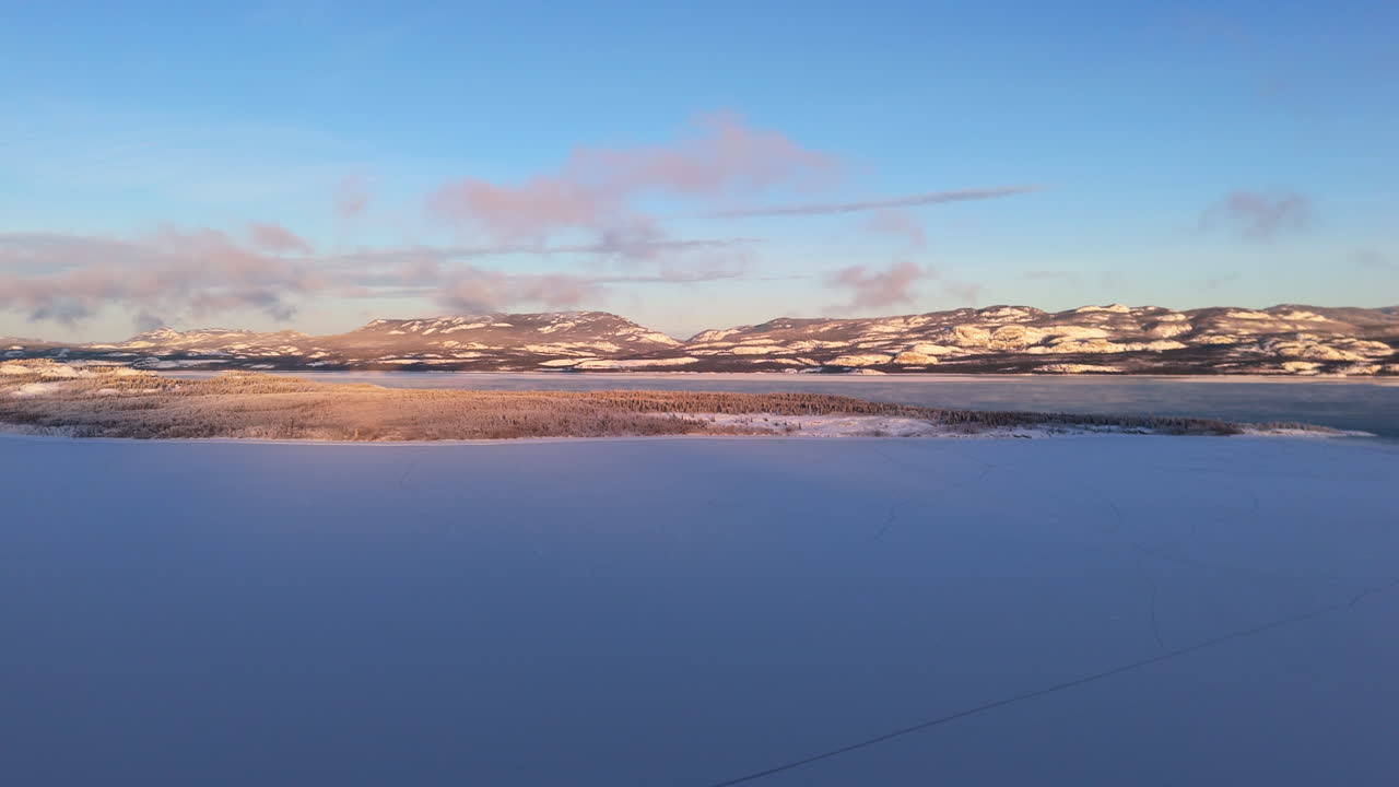 Frozen Lake Laberge With Snow-covered Mountains In The Background In Yukon, Canada. - aerial shot