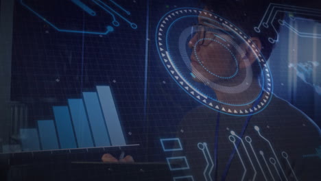 man wearing eyeglasses using tablet in tech hub, displaying holographic bar chart and circuit lines