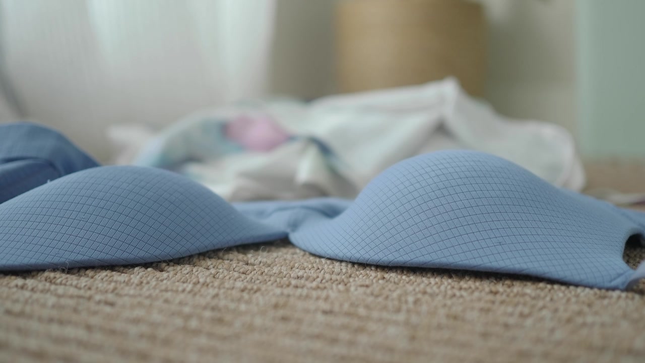 Primo piano di un reggiseno azzurro adagiato su un tappeto a trama
