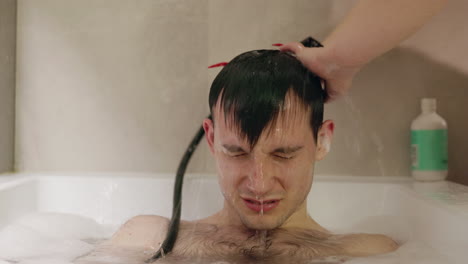 persona que se lava el cabello en una bañera