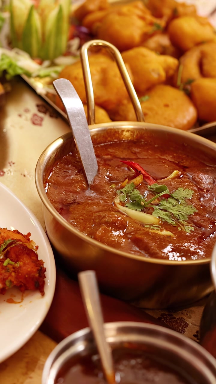 Primo piano di un commensale che usa un cucchiaio per mangiare curry e naan a Bangkok.