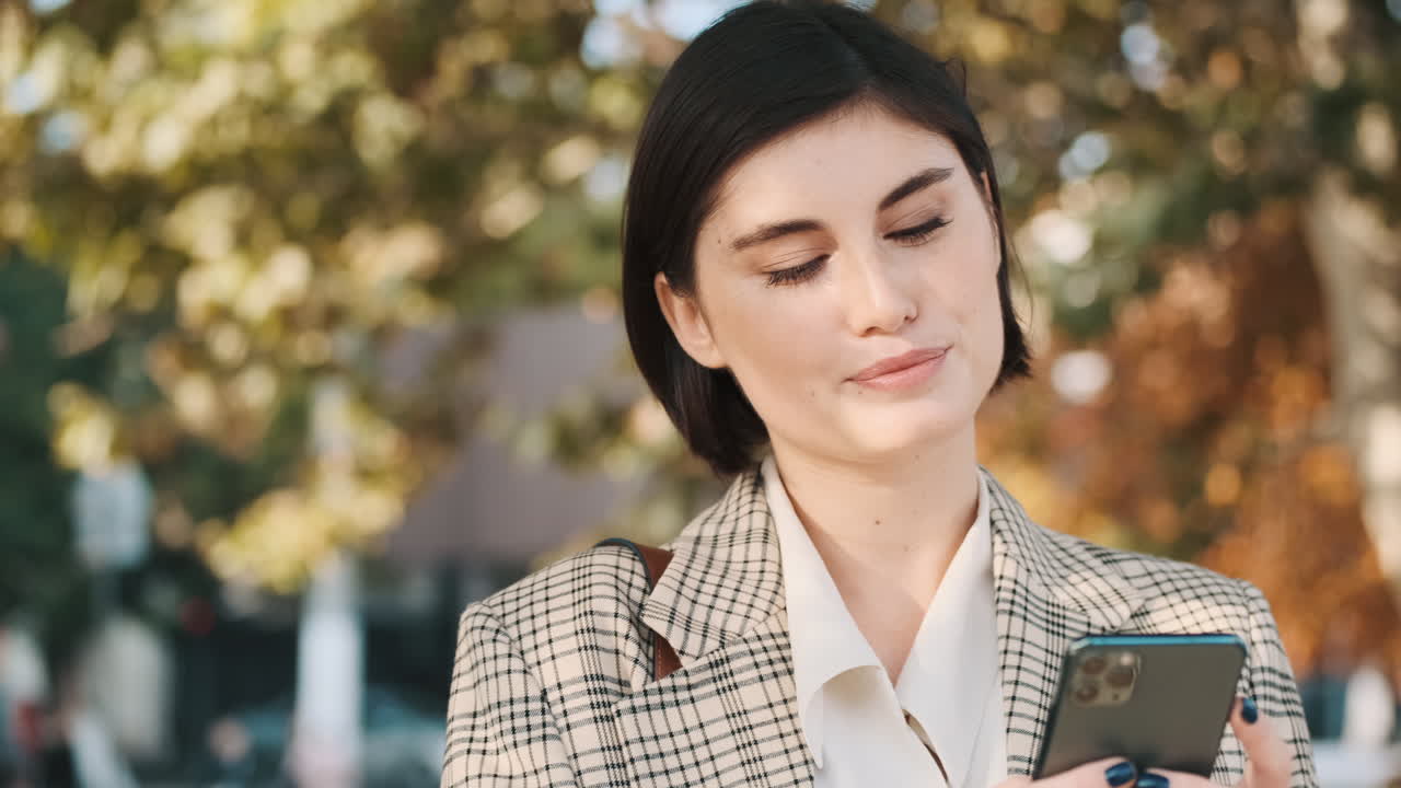 una mujer de negocios elegante usando un teléfono inteligente al aire libre.