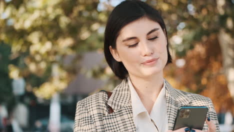 una mujer de negocios elegante usando un teléfono inteligente al aire libre.