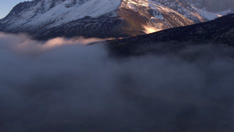 Aerial-Pan-Up-Above-Clouds-Beside-Magallanes-Region-Mountains-During-Golden-Hour