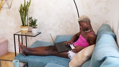 person using a laptop while relaxing on a couch at home