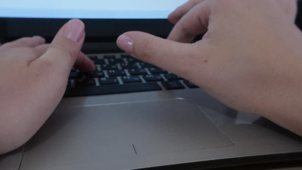 Front perspective of hands typing on a laptop keyboard. Home office productivity, digital workflow