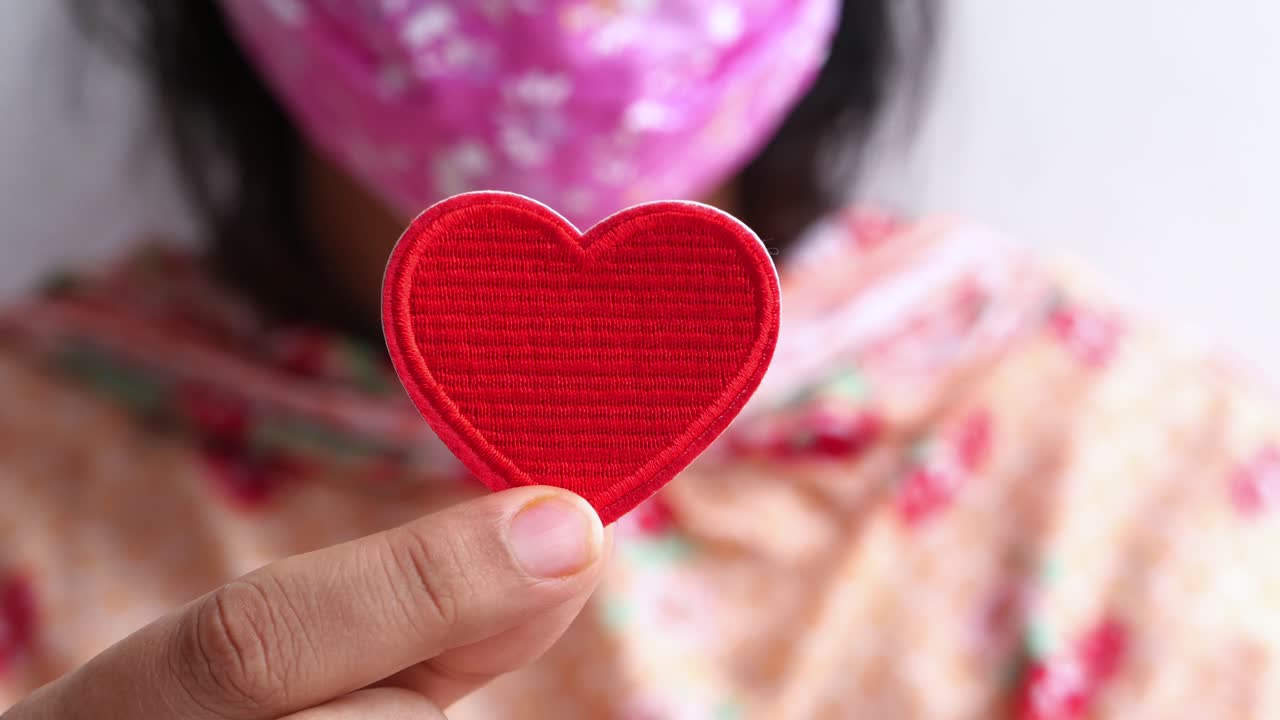 빨간색 심장 모양의 패치를 들고 있는 여자