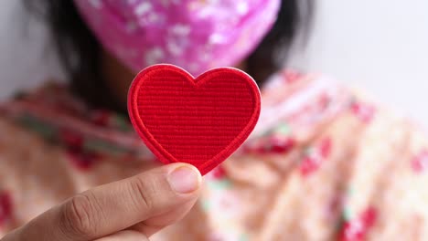 mujer sosteniendo un parche rojo en forma de corazón