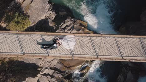 newlyweds. bride and groom lie on a bridge over a mountain river. aerial view