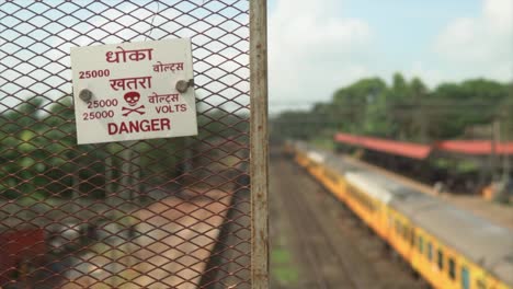 dolly shot to the right of danger sign board and ac train standing at the station