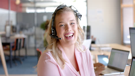 Retrato-De-Una-Feliz-Mujer-De-Negocios-Caucásica-Casual-Usando-Auriculares-Telefónicos-En-La-Oficina,-Cámara-Lenta