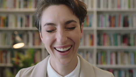 close-up-portrait-of-young-professional-business-woman-laughing-enjoying-silly-fun-making-faces-spontaneous-female-wearing-stylish-suit-in-library-office-background