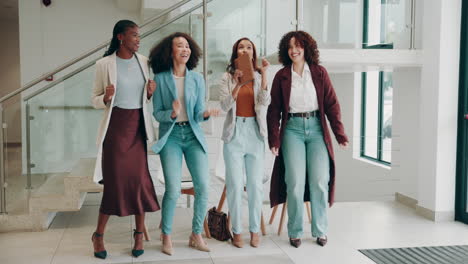 four women colleagues dancing and celebrating together in an office