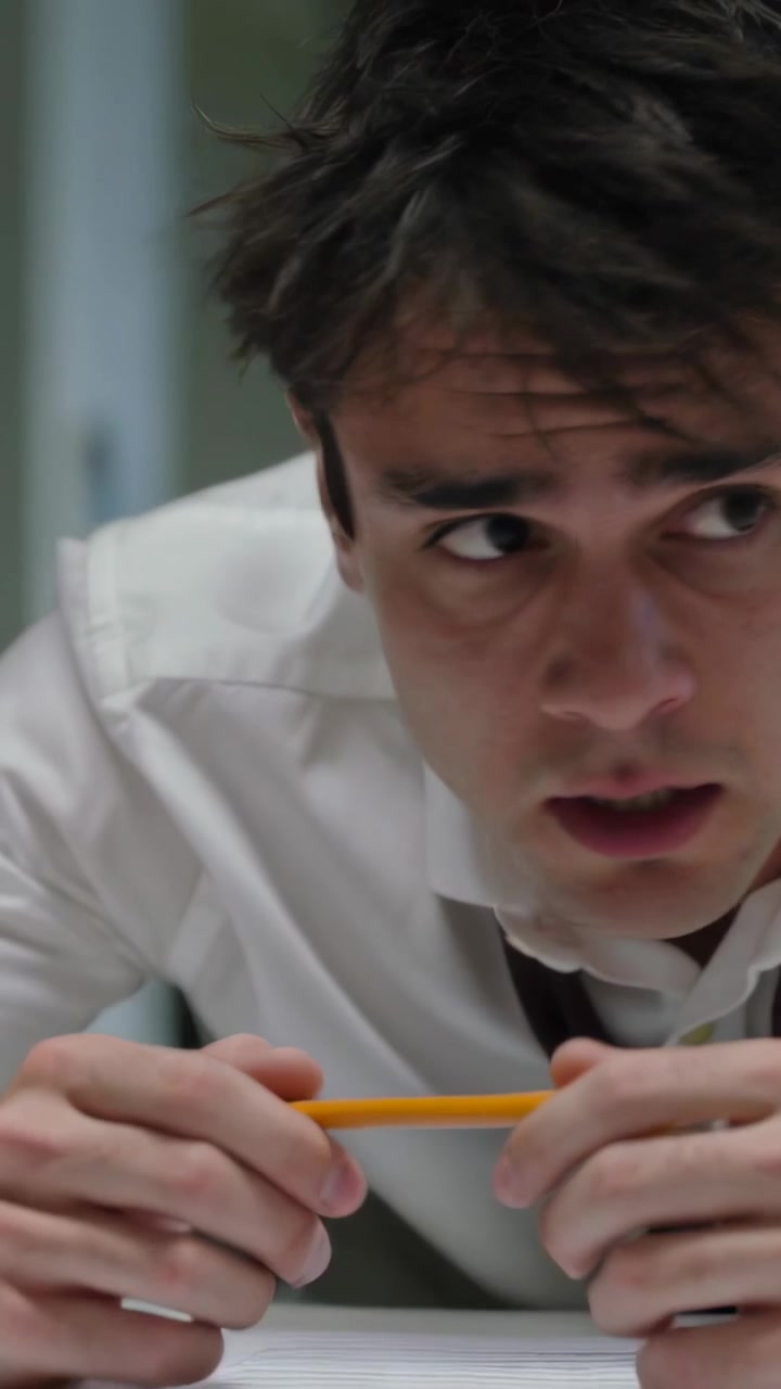Video verticale: Uomo in camicia e cravatta che, vedendo un segnale fuori campo, sposta documenti alla scrivania, tendendosi e stringendo una matita