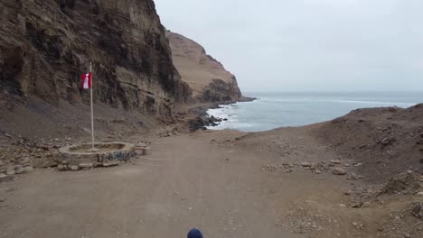 drone video flying over person walking down a path next to cliff side and ocean coast