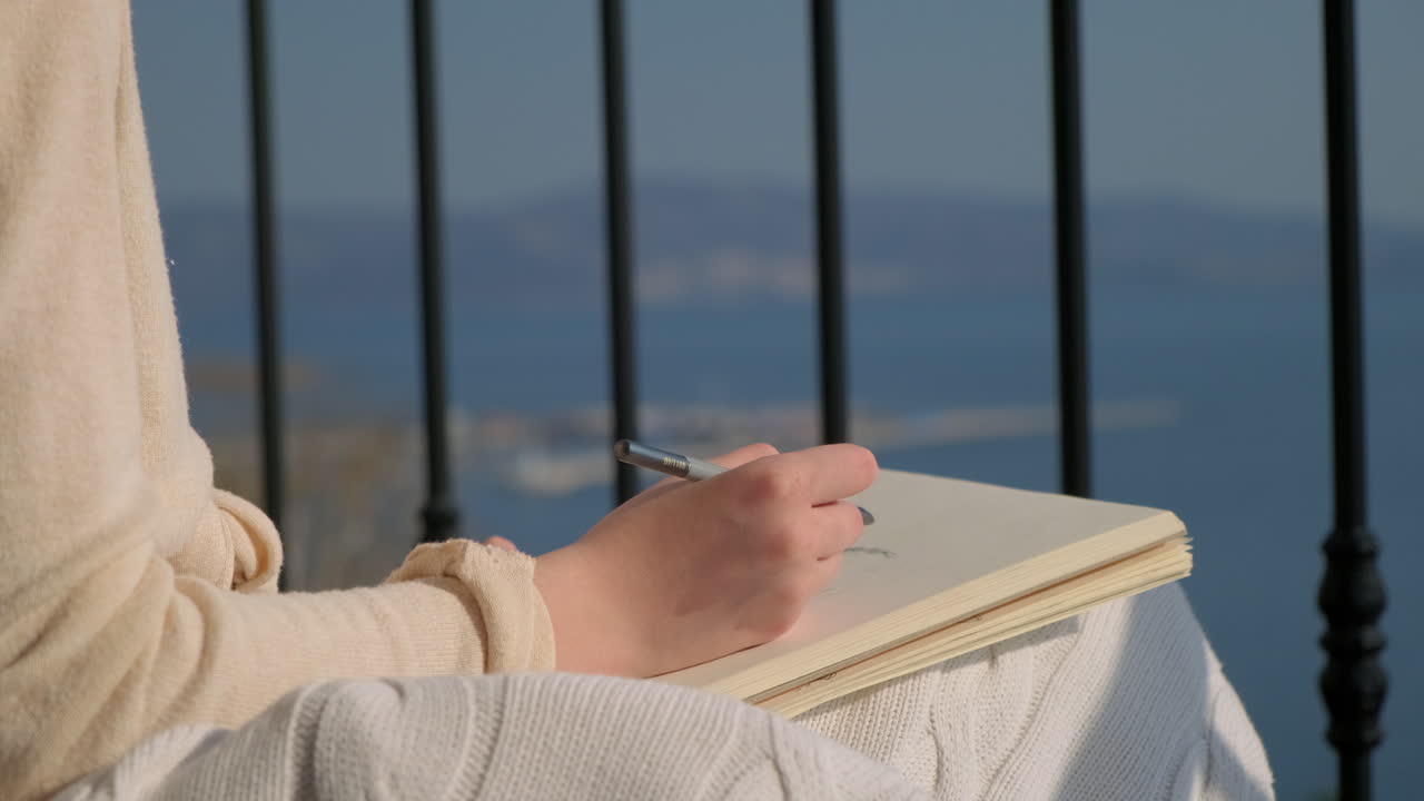 Woman Sketching on a Balcony with a Sea View