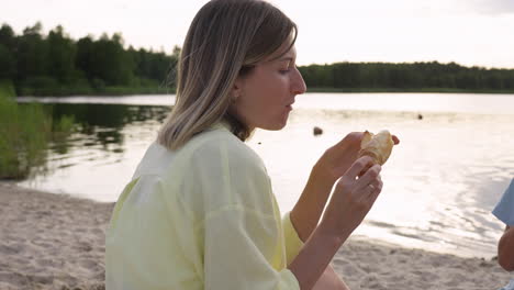 kobieta jedząca croissant na plaży.