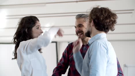 Smiling-young-friends-talking-and-giving-high-five