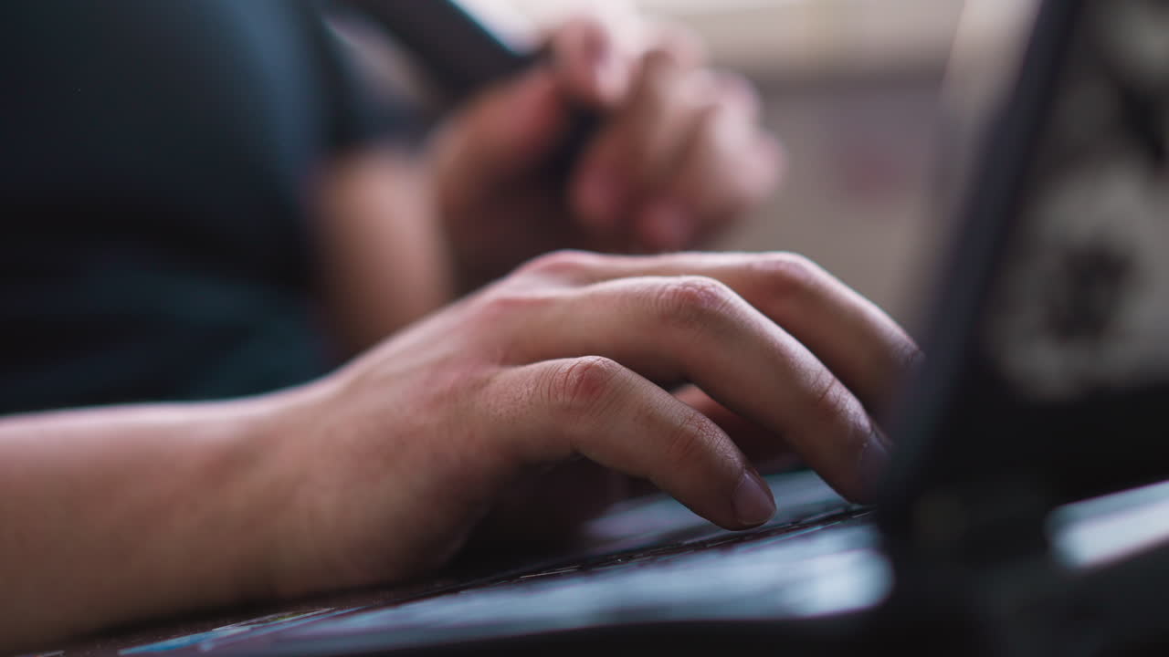 Man with electronic cigarette works on notebook keyboard
