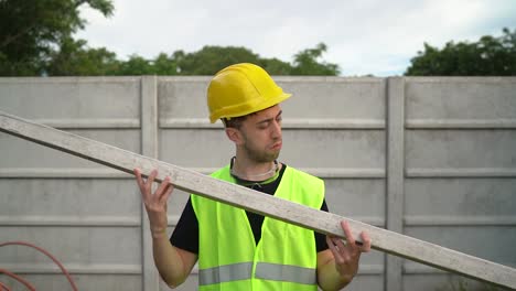 Un-Trabajador-De-La-Construcción-Que-Lleva-Un-Casco-Amarillo-Está-Examinando-Madera-Pintada-En-Blanco---Primer-Plano-Medio