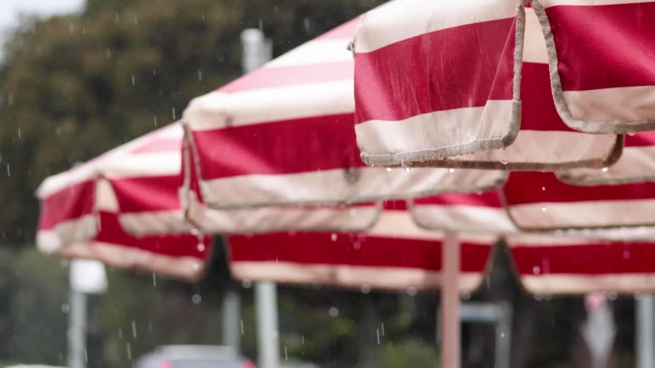 gotas de lluvia cayendo en paraguas de rayas rojas al aire libre