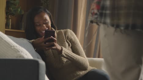 man sitting next to woman on sofa at home using mobile phone and talking