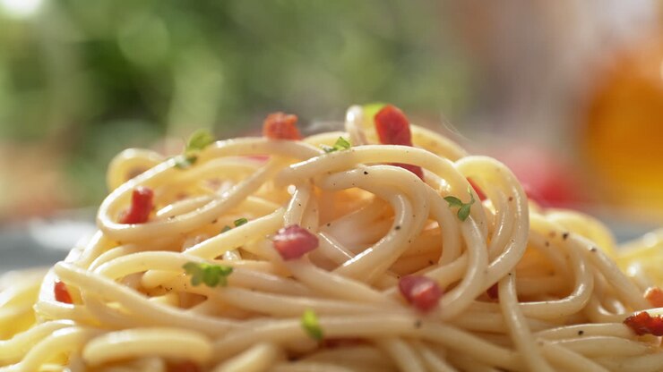 Spaghetti Carbonara - Freshly Prepared, Ready to Eat, Hot and Steaming Dish on a Bright Plate on the Kitchen Counter in Slow Motion