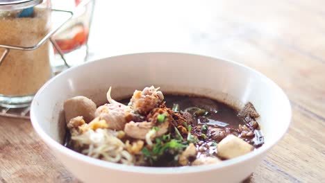 adding spices to a bowl of noodle soup