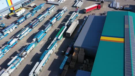 aerial view of a semi trucks with cargo trailers standing on warehouses ramps for loading unloading goods on the big logistics park with loading hub