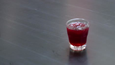 mano recogiendo un vaso de bebida de jugo de rosella de la mesa