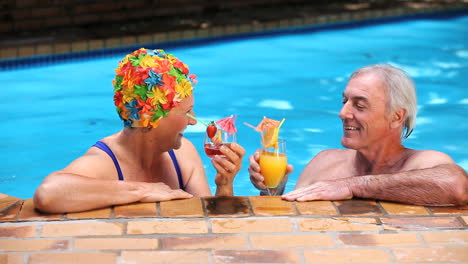 ancianos brindando con cócteles en la piscina