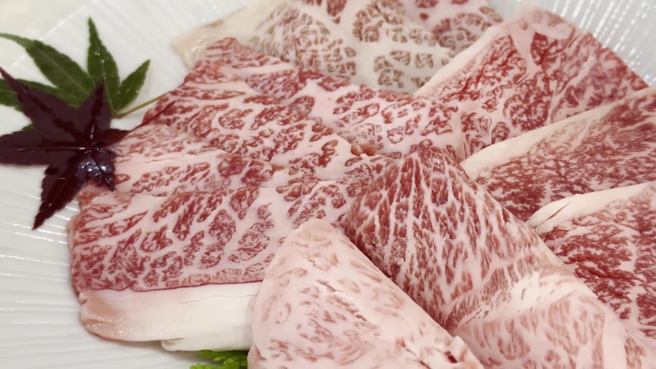 Primer plano de rebanadas de carne de res Wagyu A5 premium dispuestas en un plato de servir, destacando un marmoleado excepcional y una presentación elegante para una cena gourmet.