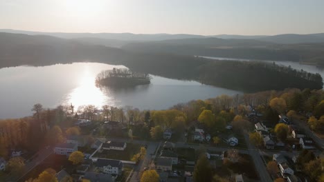 aerial pan and push, in the sunny autumn sky featuring a beautiful suburban area during the fall time, positioned next to a big lake