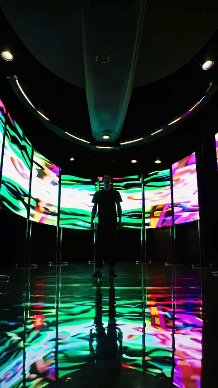 A person stands in a futuristic room with vibrant digital screens