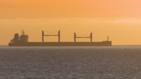 Floating-on-Cascais-Bay,-a-fishing-boat-moving-slowly-over-the-water-and-a-commercial-jet-airplane-crossing-frame